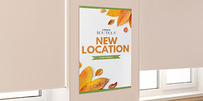 A new location printed poster for a boutique hanging on a wall