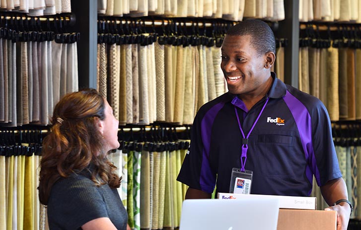 FedEx Office team member speaking with woman business employee while delivering parcel