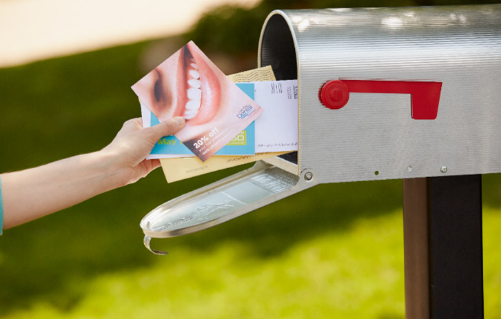 woman retrieving direct mail materials from outdoor mailbox