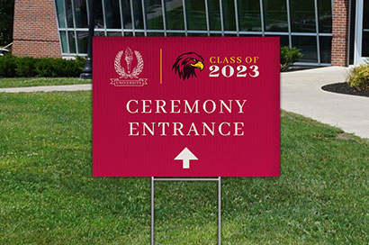 A printed yard sign directing people to the ceremony entrance for a graduation