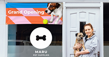 Woman holding puppy standing outside of her pet supply business