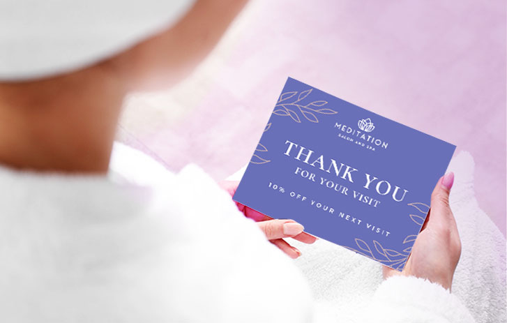 A customer holding a thank you card from a spa with a discount for their next visit