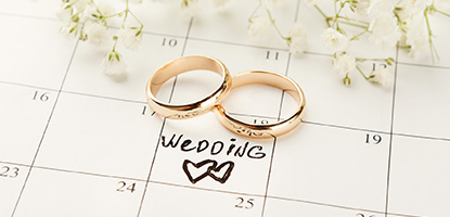 engagement rings laying on calendar marked with wedding date